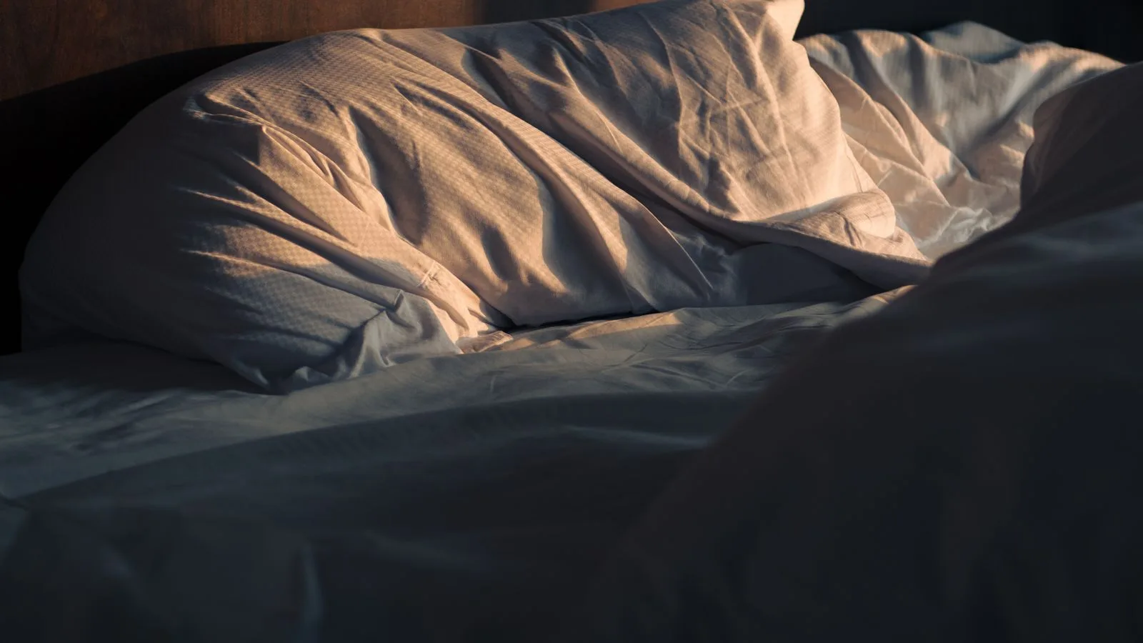Las sábanas de una cama en penumbra