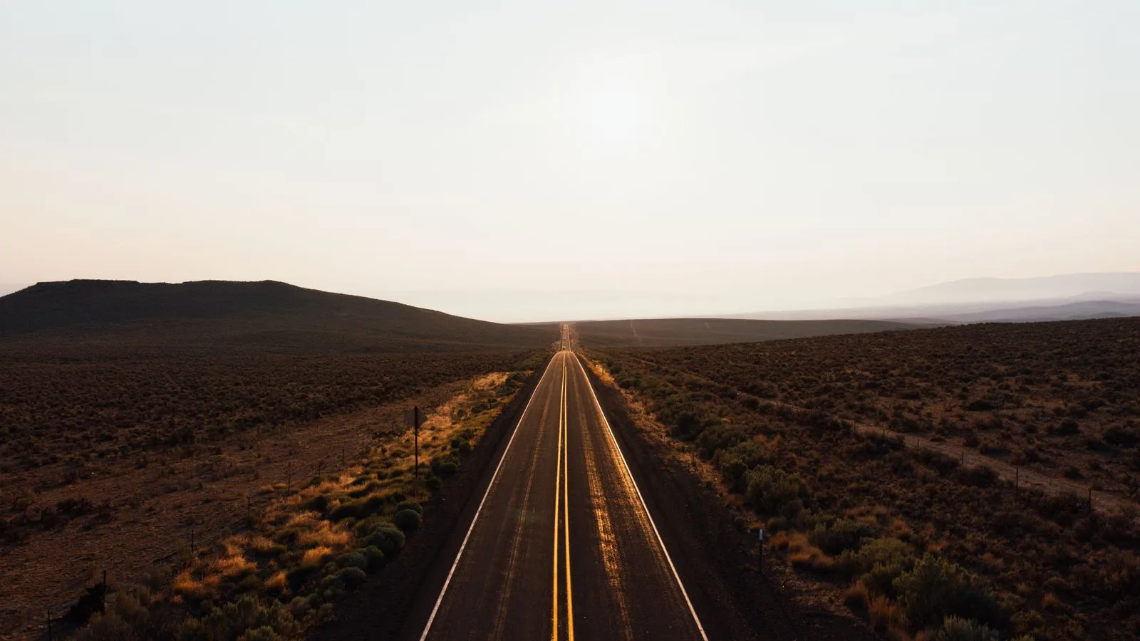 Una carretera larga que se pierde en el horizonte al atardecer