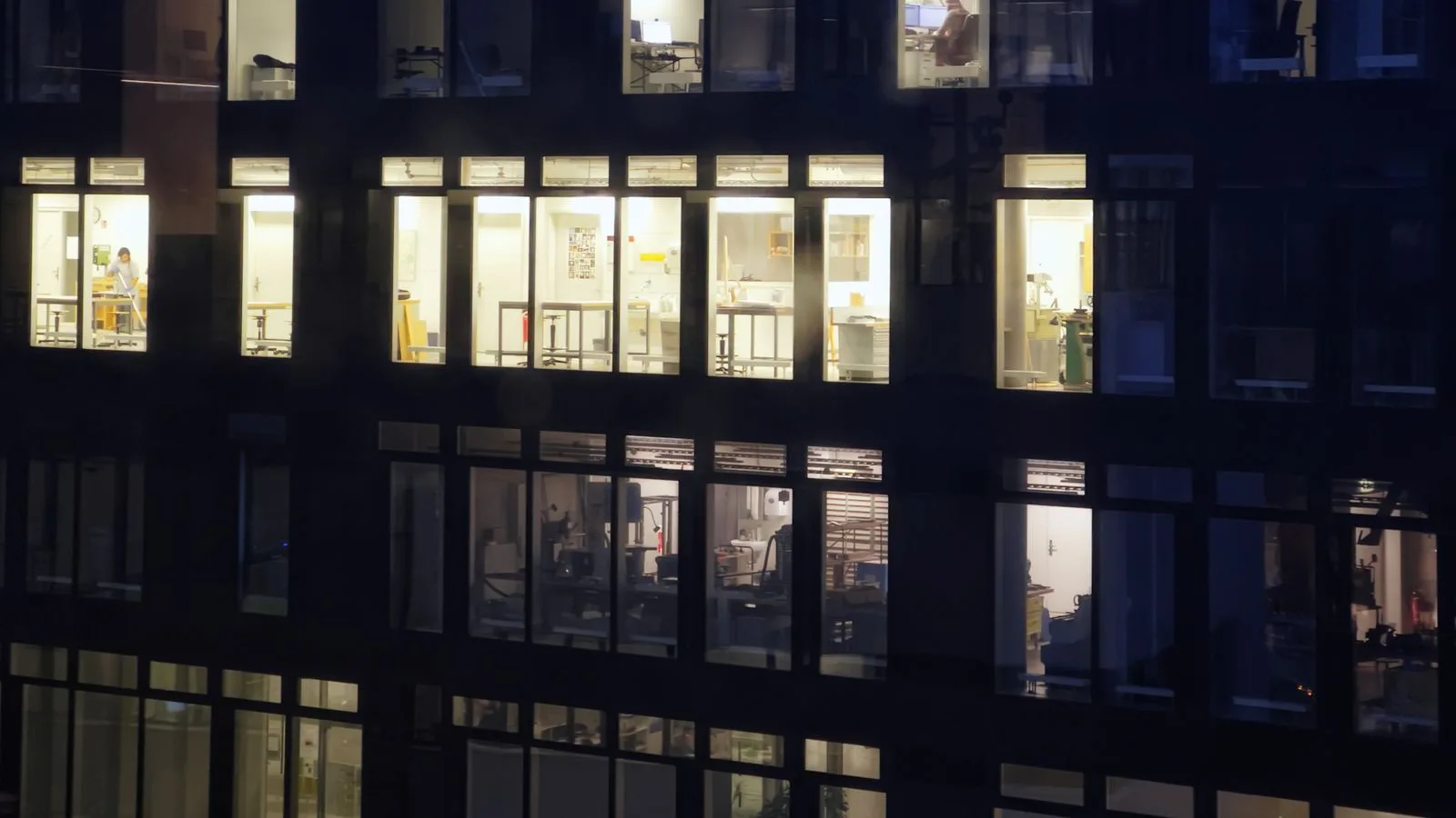 La fachada de un edificio de noche: unas cuantas ventanas iluminadas y el resto a oscuras