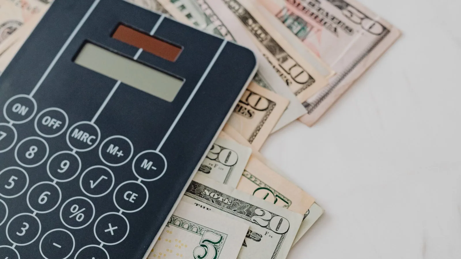 Una calculadora en blanco y negro apoyada sobre billetes