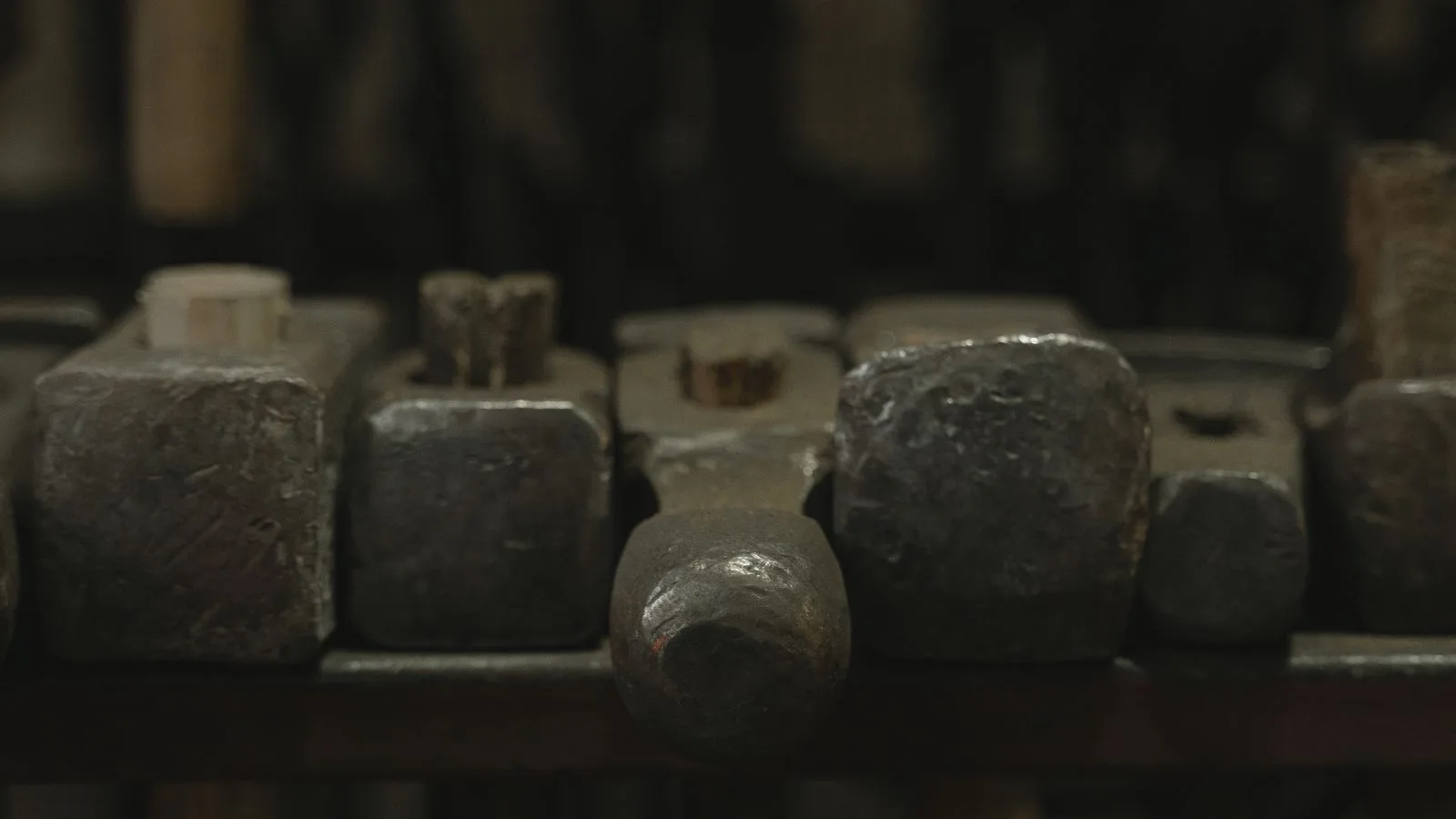 Cabezas de martillo alineadas en un estante de taller en penumbra