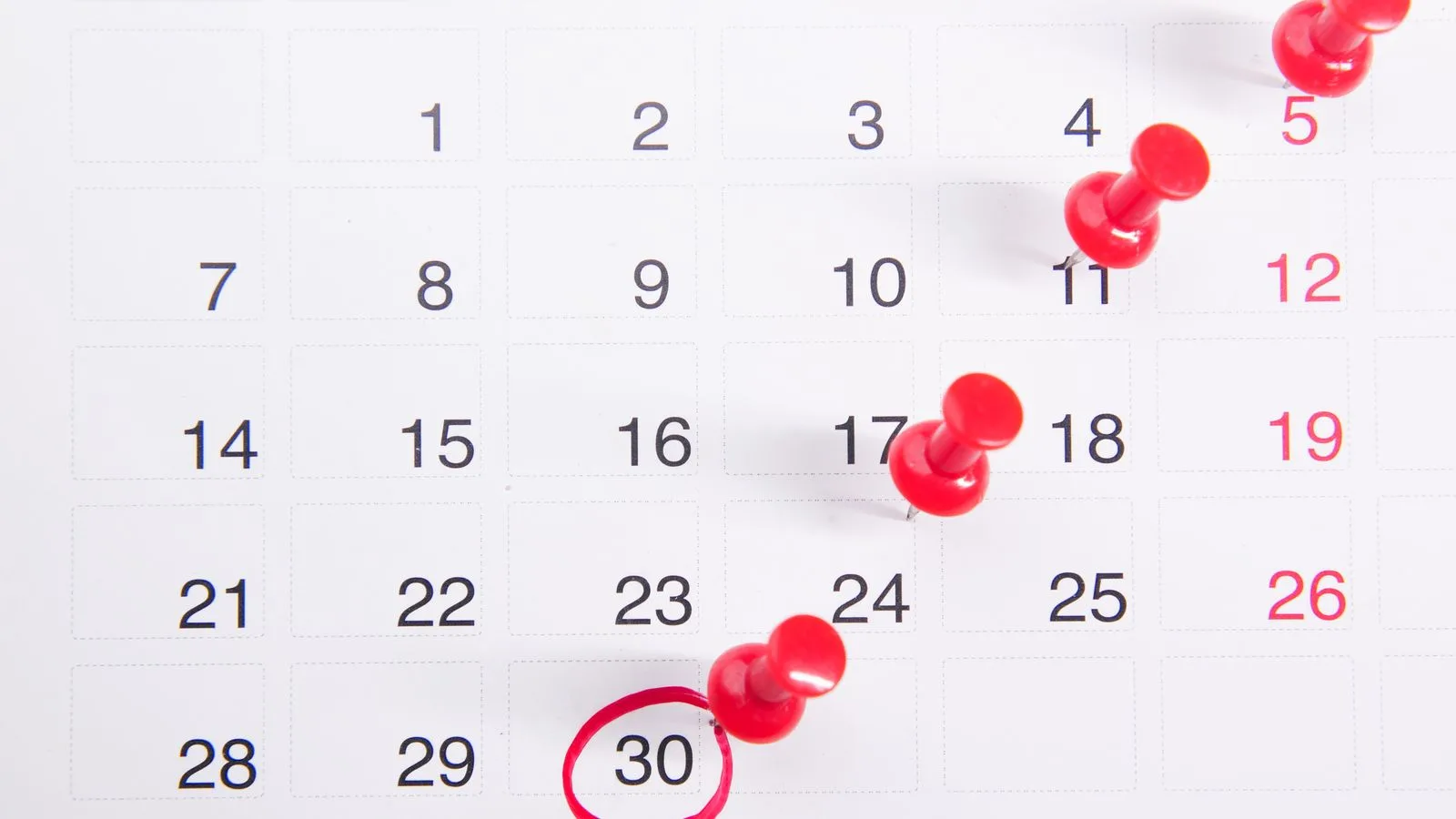 Un calendario de pared con tachuelas rojas marcando los días cumplidos