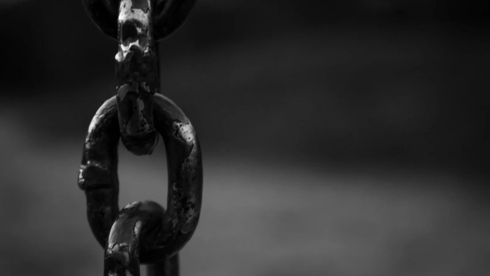 Un eslabón de cadena roto, de cerca, sobre fondo oscuro