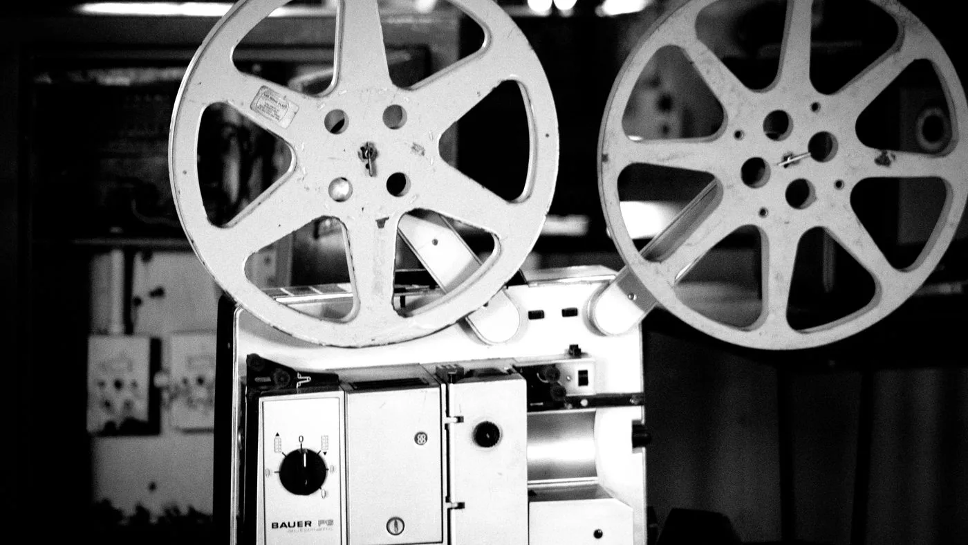 Un proyector de cine antiguo con sus carretes, en blanco y negro