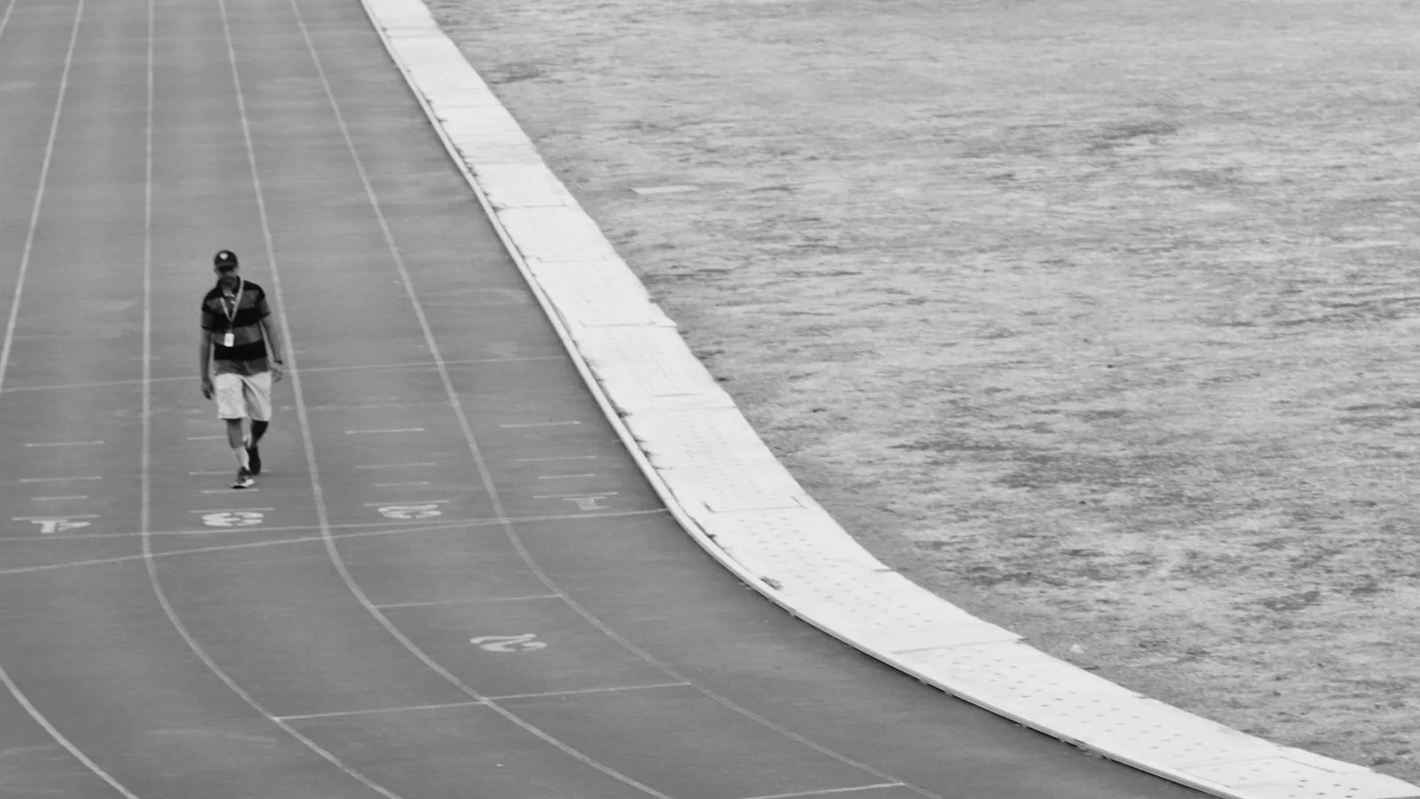 Un corredor solitario en una pista de atletismo vacía, en blanco y negro