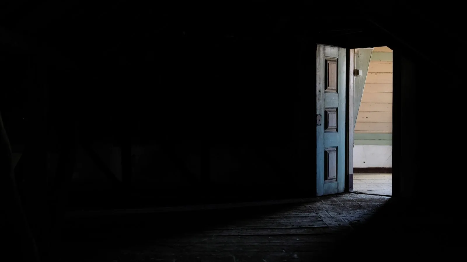 Una puerta abierta que lleva de un cuarto oscuro a un espacio iluminado