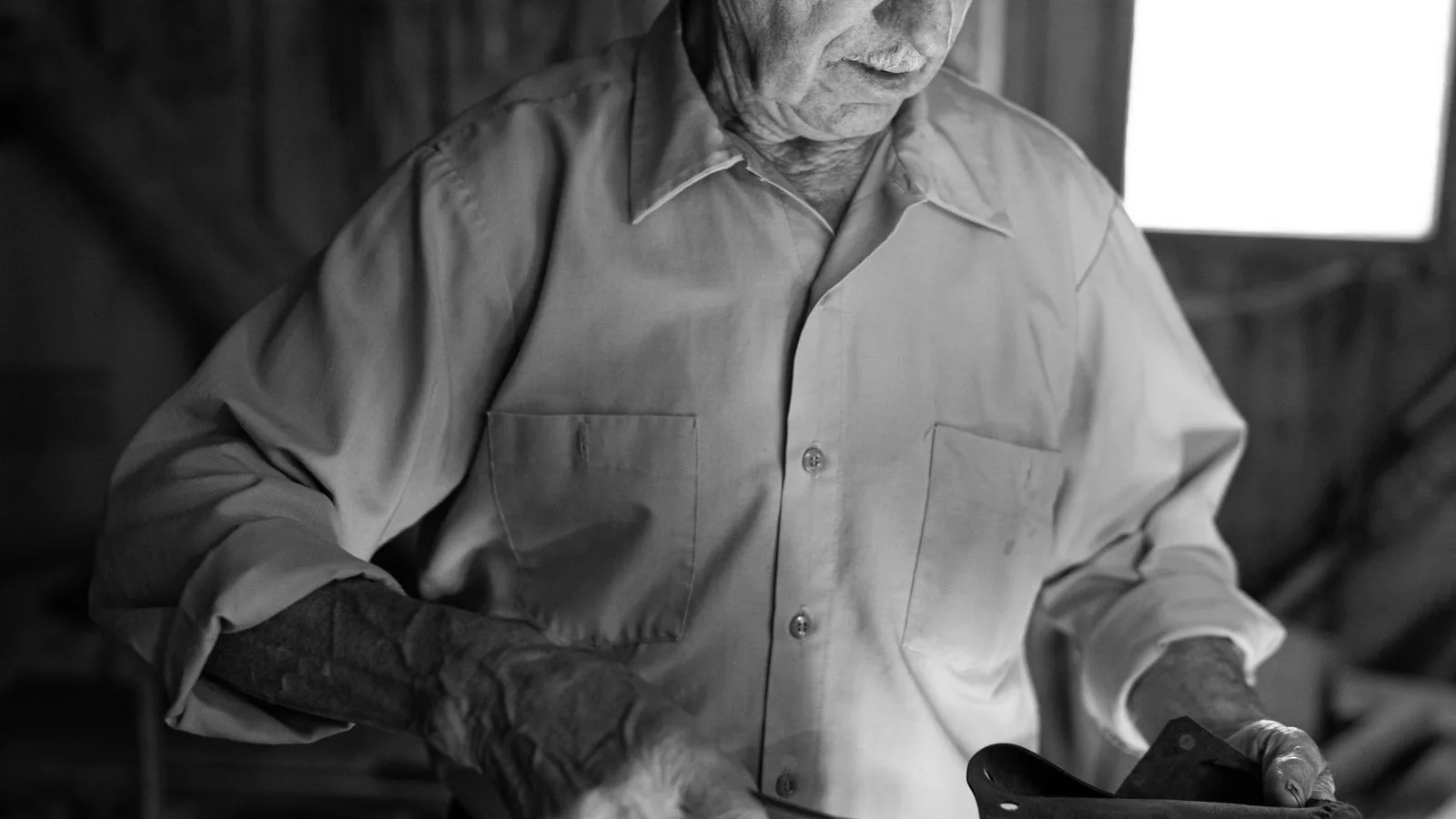 Retrato en blanco y negro de un hombre mayor con las manos trabajadas