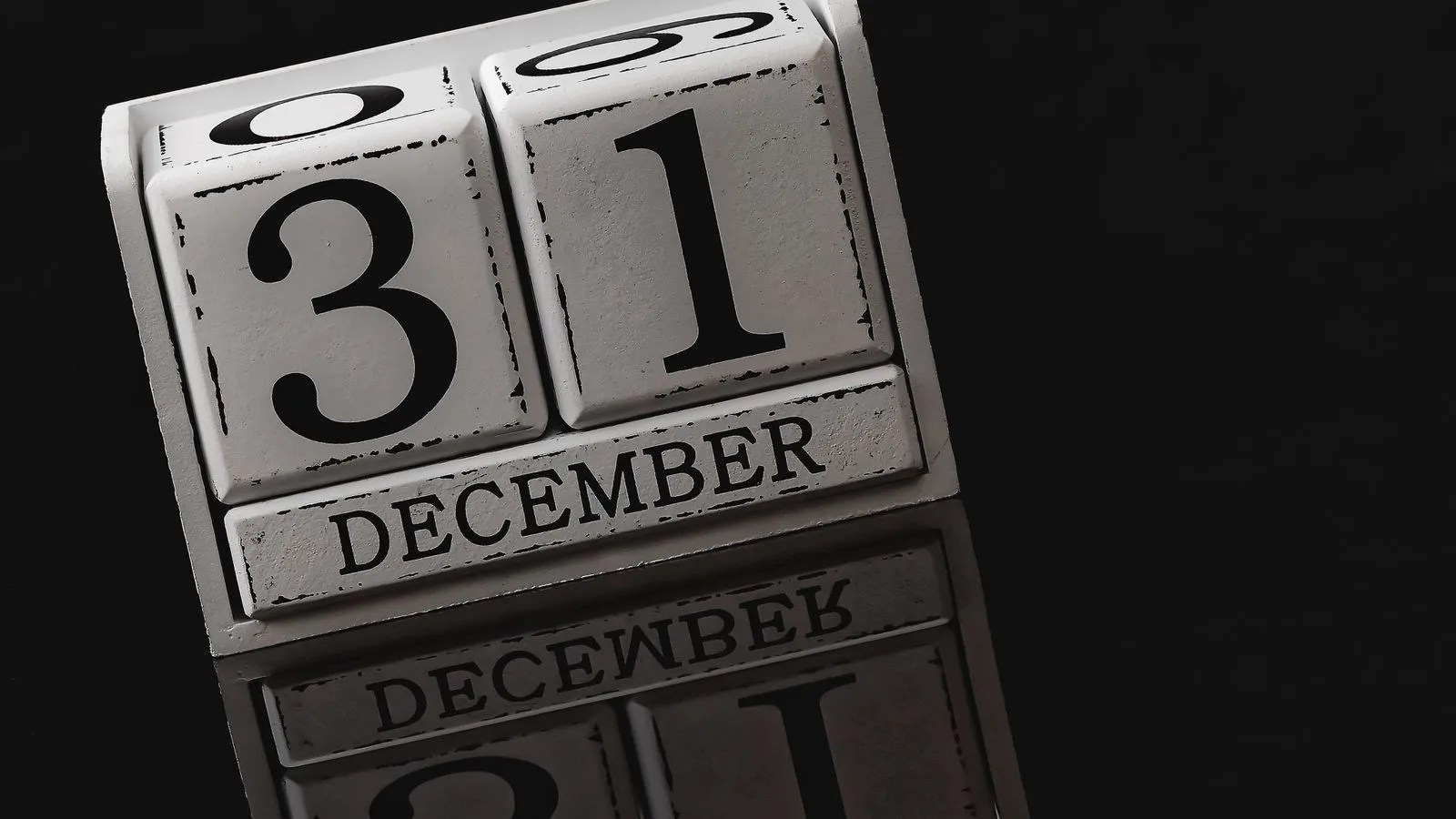 Un calendario de cubos de madera marcando una fecha, sobre fondo oscuro