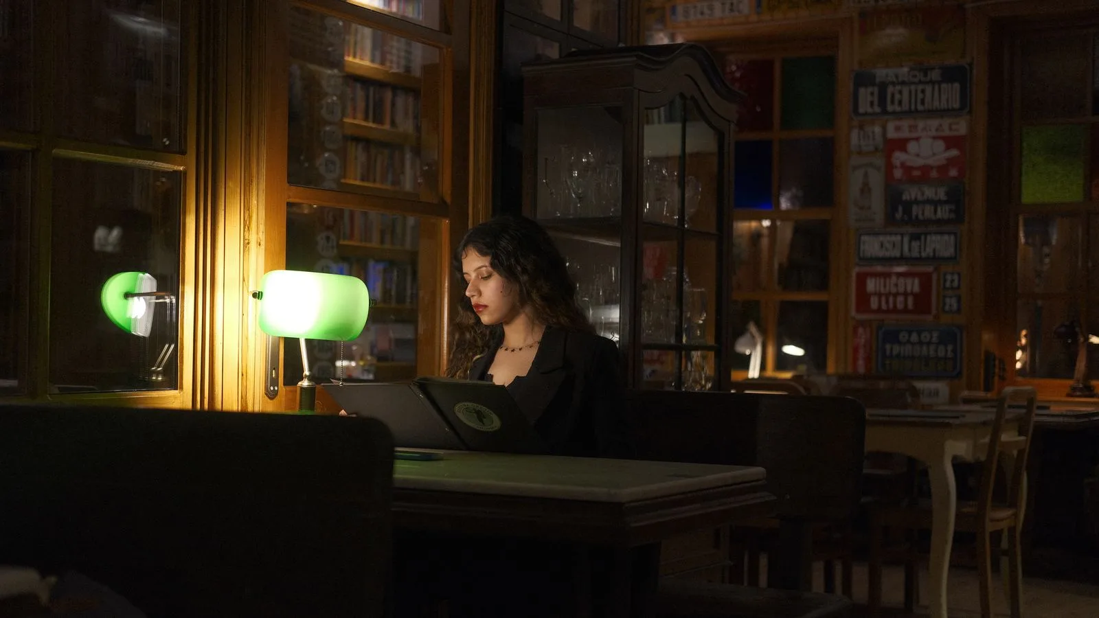 Alguien estudiando de noche en una biblioteca con lámpara encendida