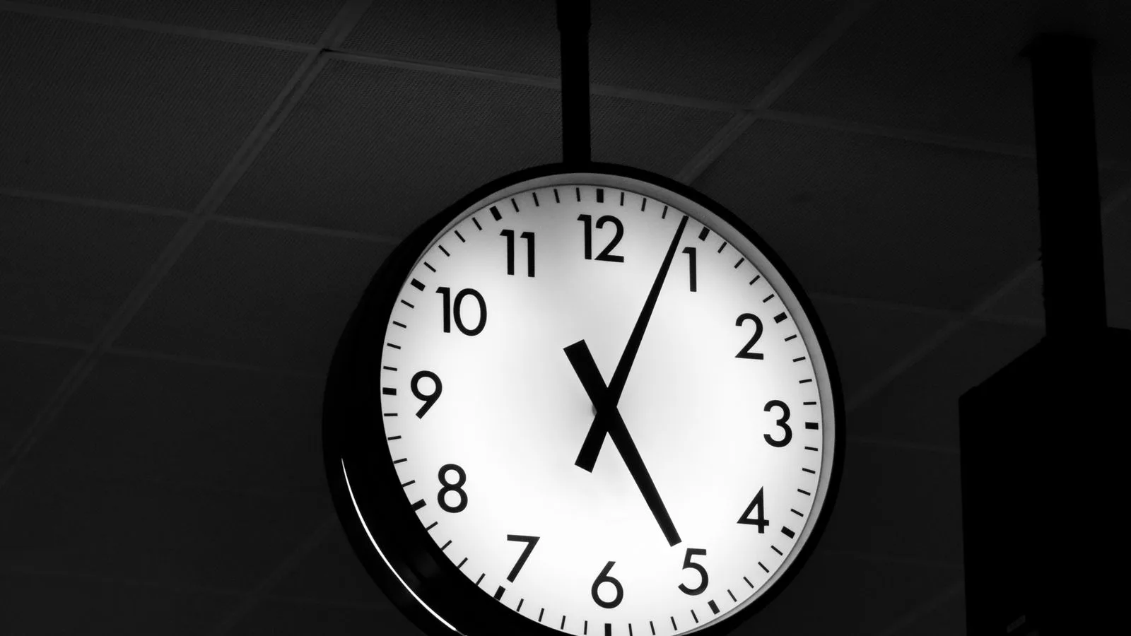 Un reloj de pared negro sobre fondo oscuro