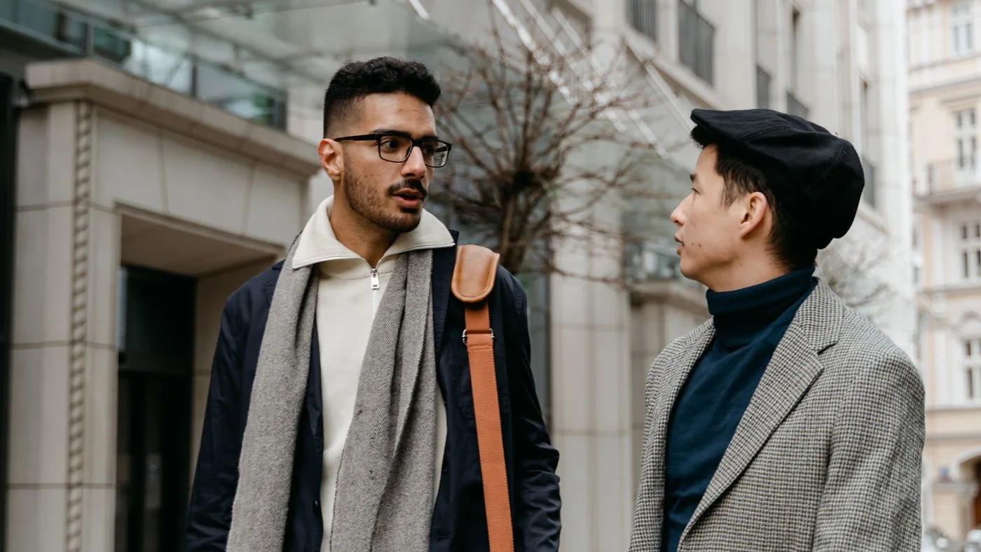 Dos hombres conversando de pie en la calle