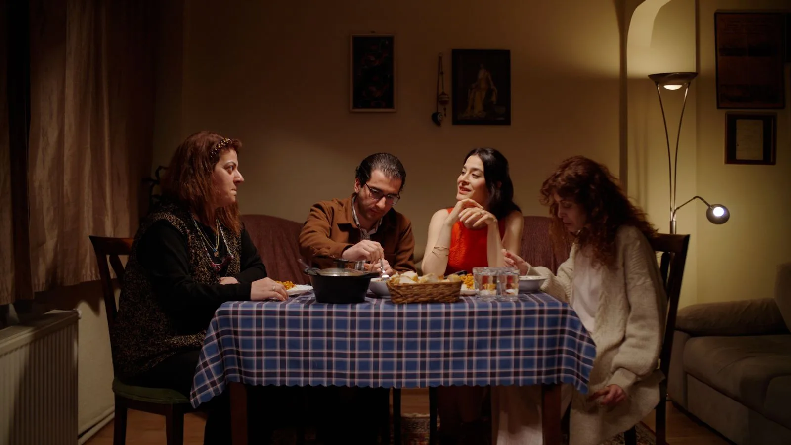 Una cena familiar alrededor de la mesa, en una habitación en penumbra